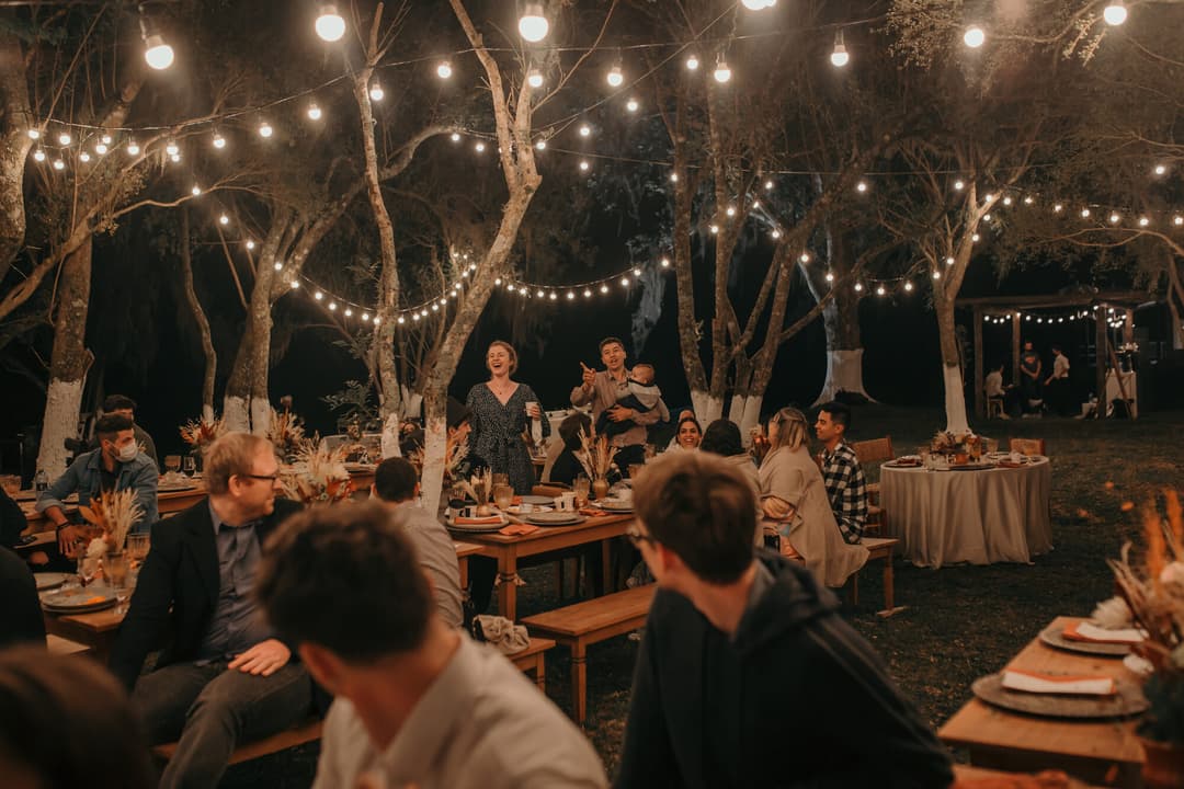 Jantar de recepção à noite, com luzes entre as árvores
