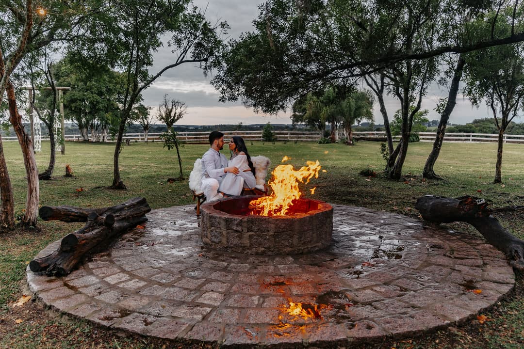 Casal à beira da fogueira ao entardecer